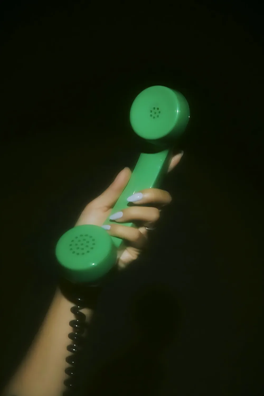 A hand holding a green telephone receiver